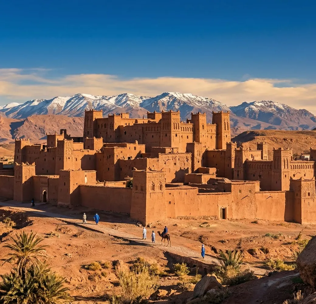 Kasbah en pisé ocre de Ouarzazate se détachant sur les montagnes de l'Atlas et le ciel désertique